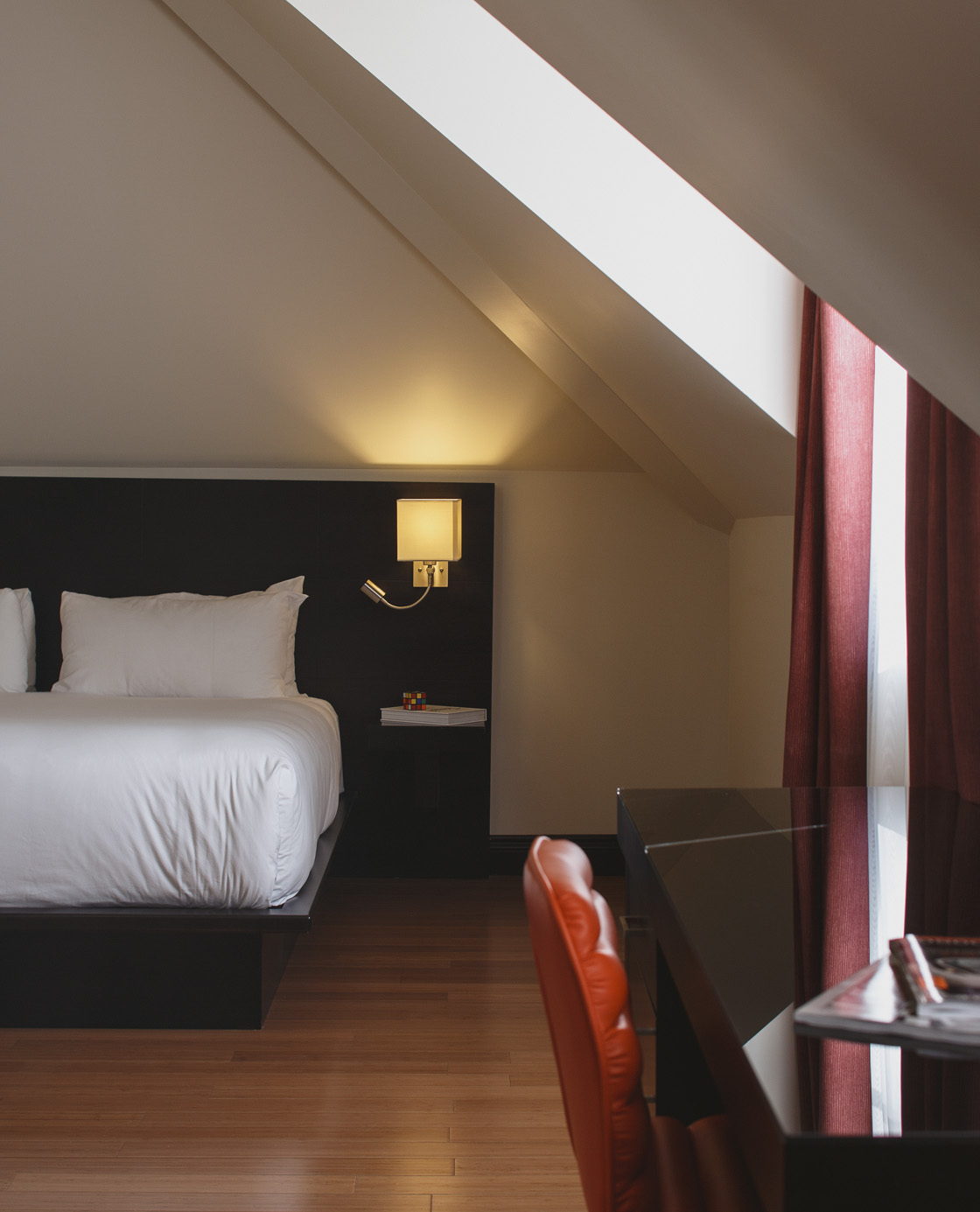A bed, table and desk chair in one of the rooms of Le Petit Hotel.
